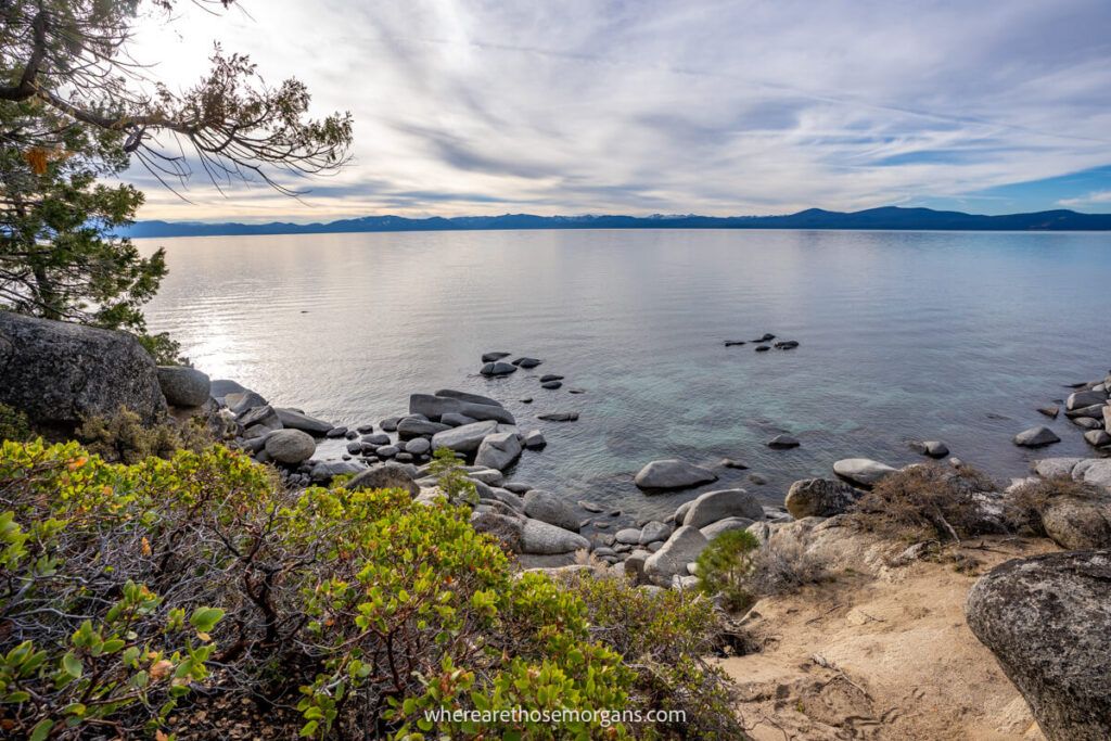 Lake Tahoe on a cloudy afternoon with rocks and trees in the foreground
