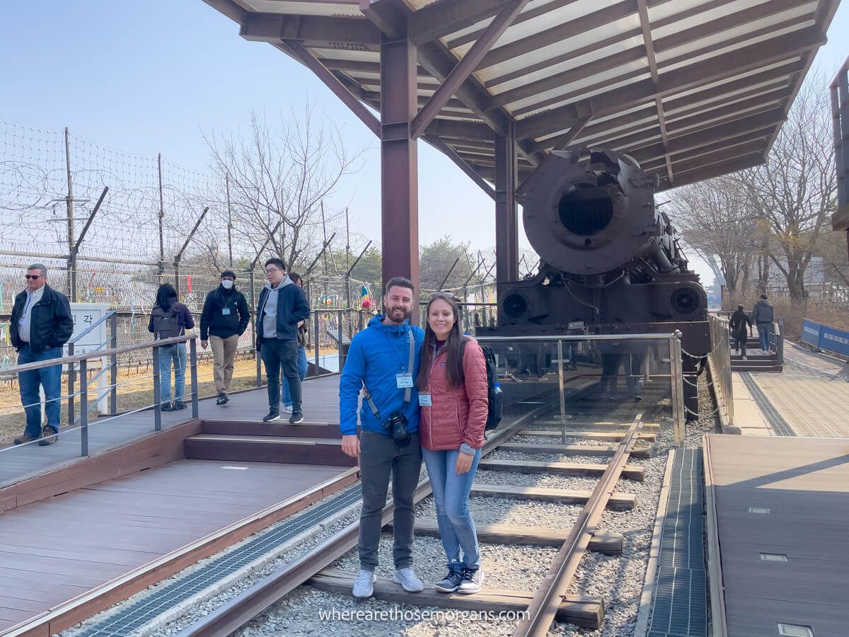 Two people posing for a photo in from of an old steam locomotive at Imjingak Park