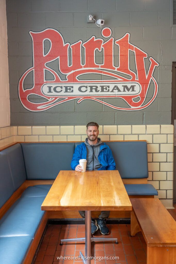 Man sitting on a wooden bench at Purity Ice Cream