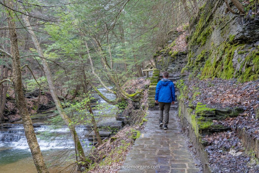 Man walking a stone path through Buttermilk Gorge in a blue raincoat