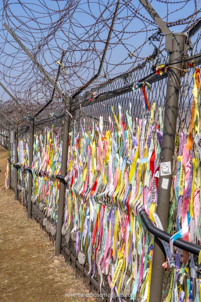 Many colorful ribbons tied to a barbed wire fence to honog abductions from the Korean War