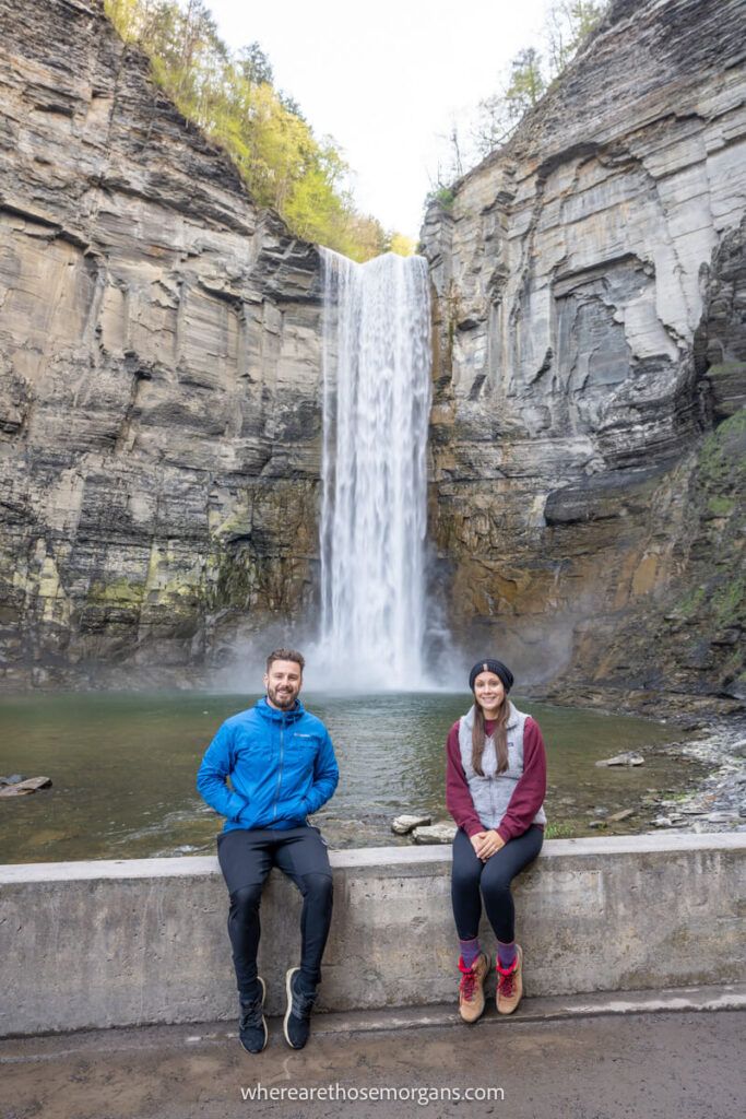 Man and woman sitting on a stone barrier and posing for a photograph at in a NY State Park