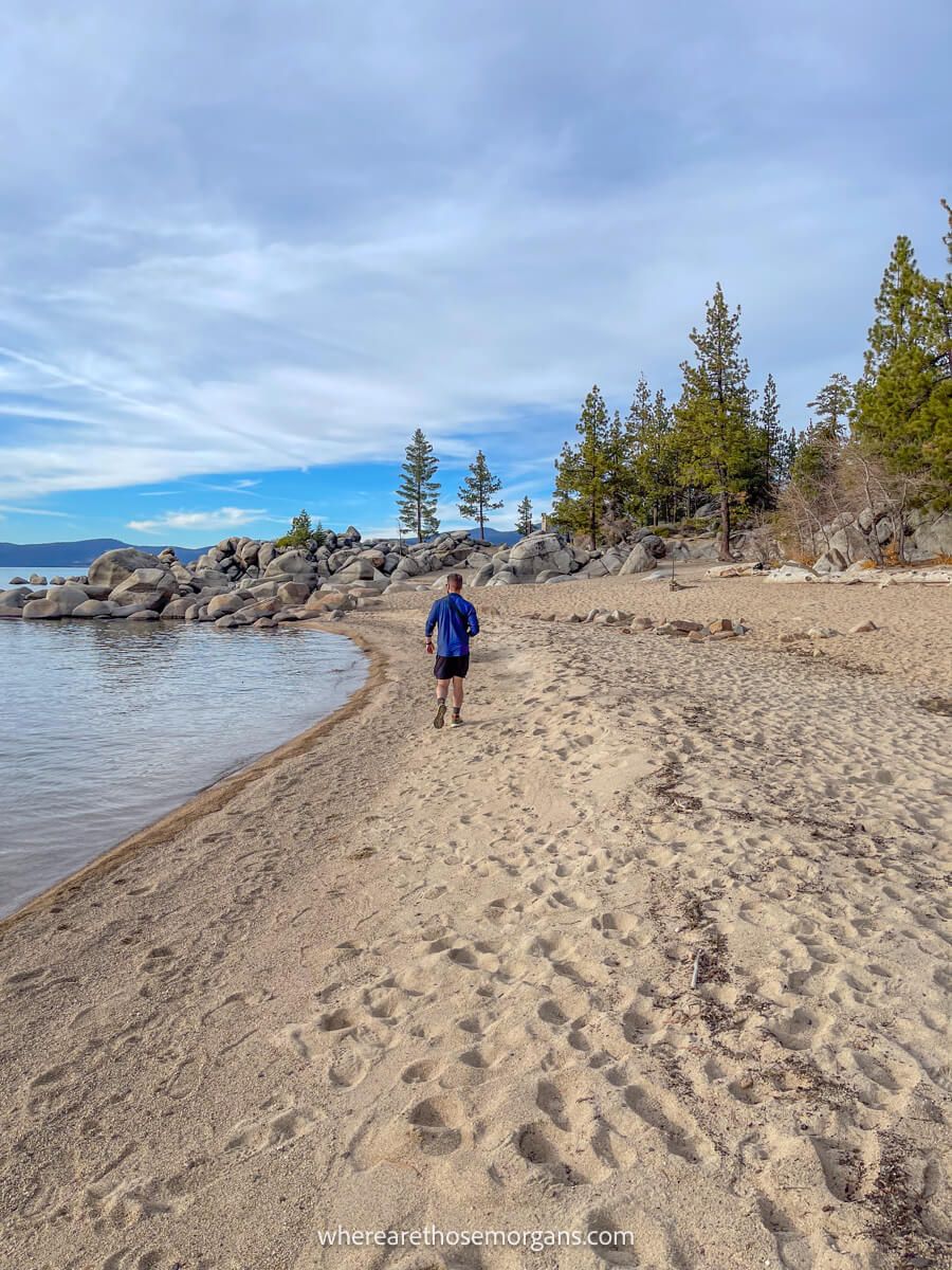 Hiker walking along a sandy beach on the shores of a lake in november