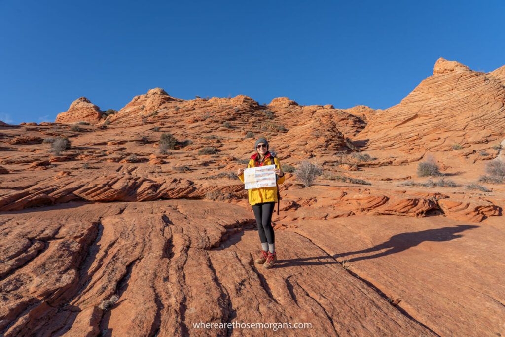 Woman holding up a paper map when hiking the wave in arizona
