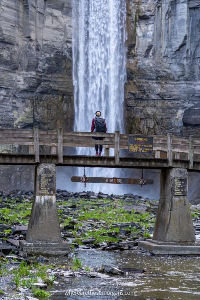 Woman standing in front of Taughannock Falls on a wooden bridge