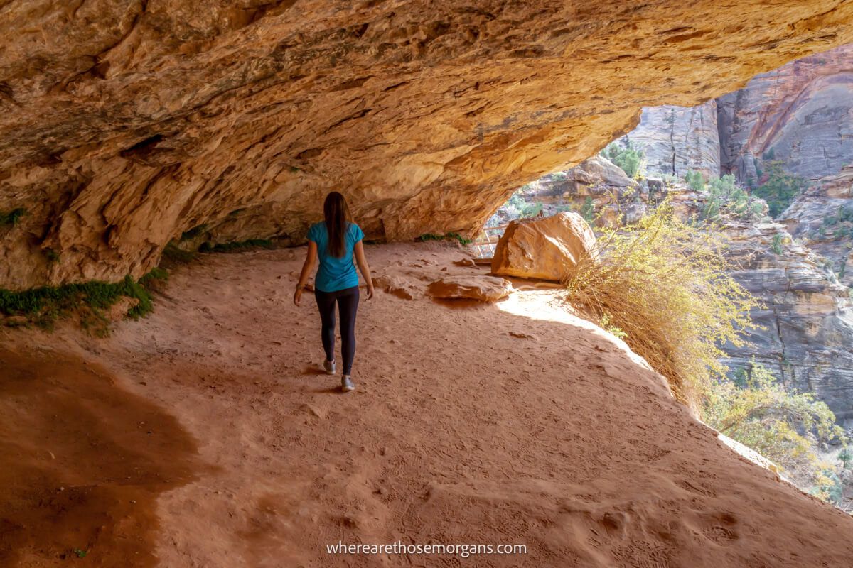 Hiker walking through a cave on a sunny day in Utah