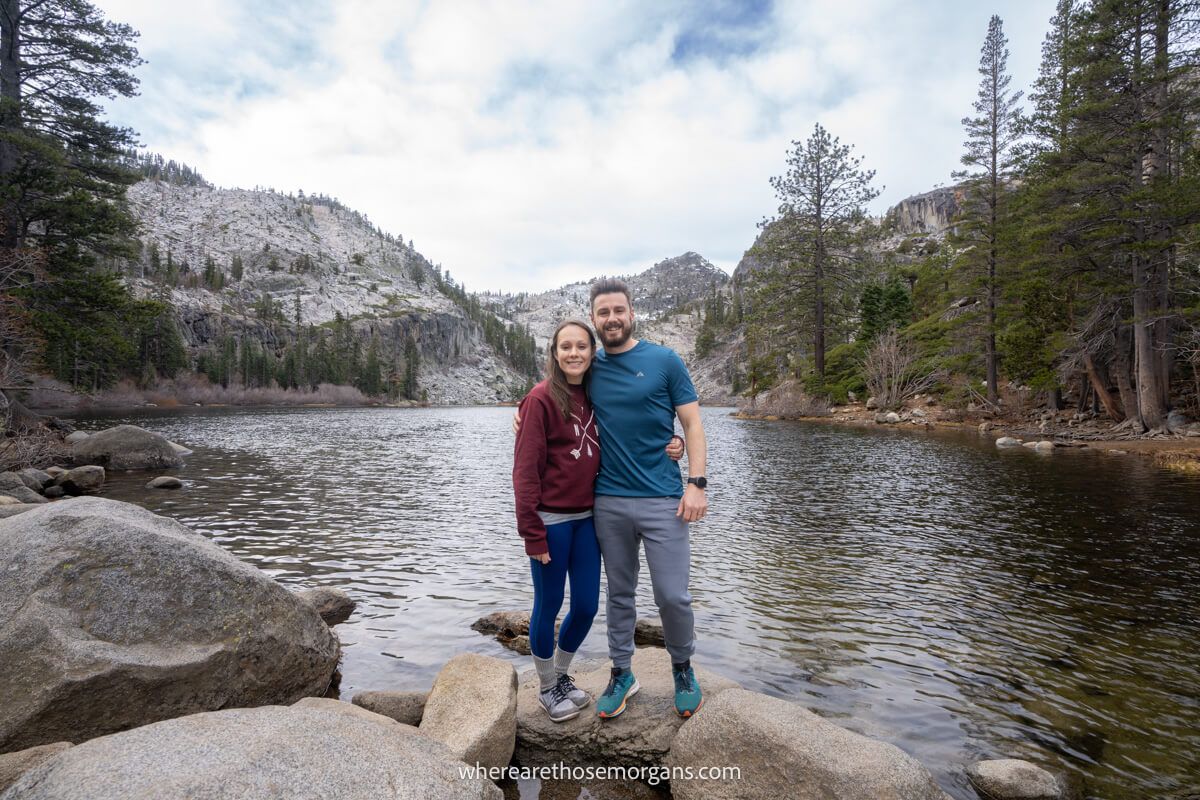Couple standing on rocks for a photo in front of a lake on the Eagle Falls trail in Lake Tahoe California