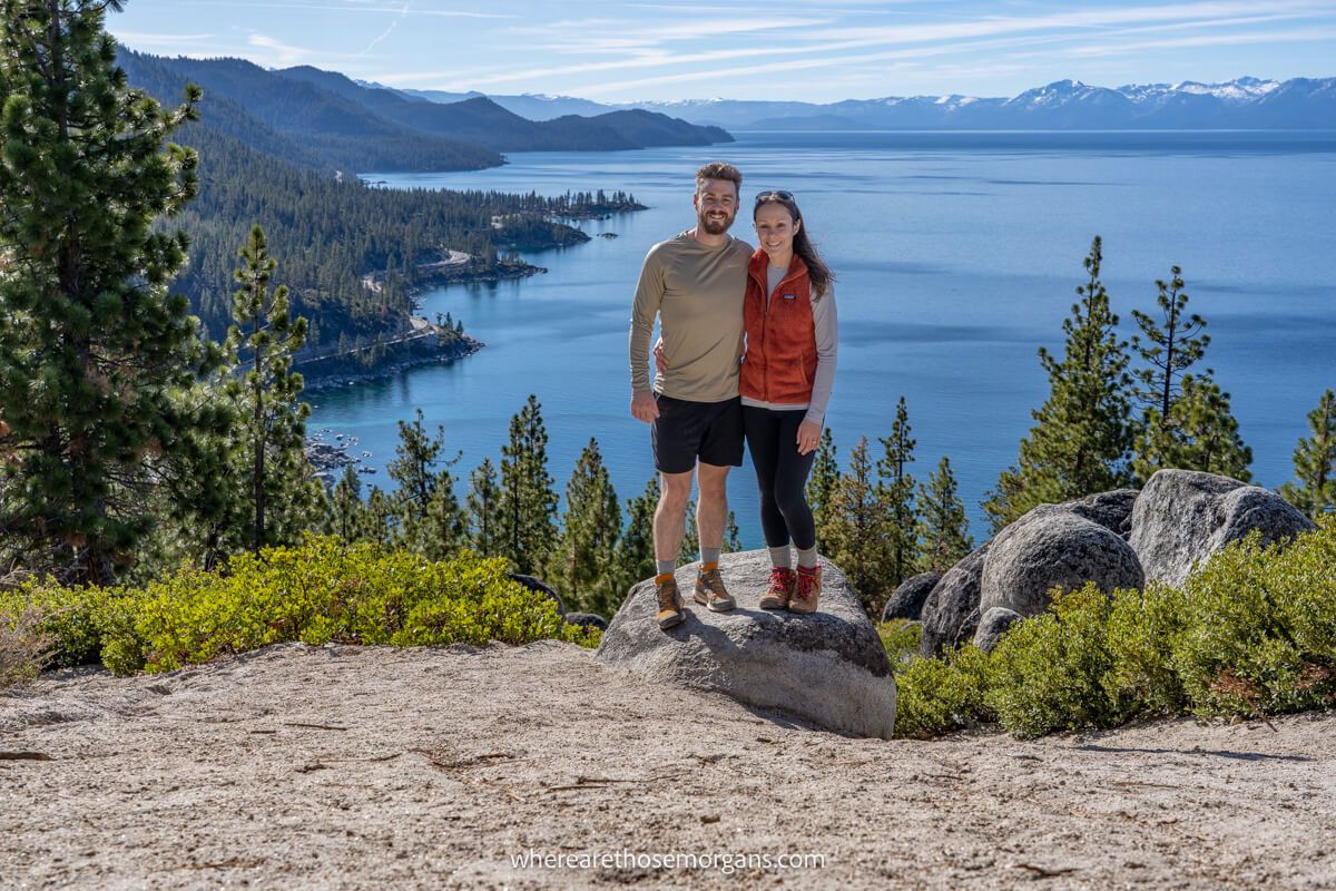 Couple hugging at a viewpoint overlooking a lake and mountains