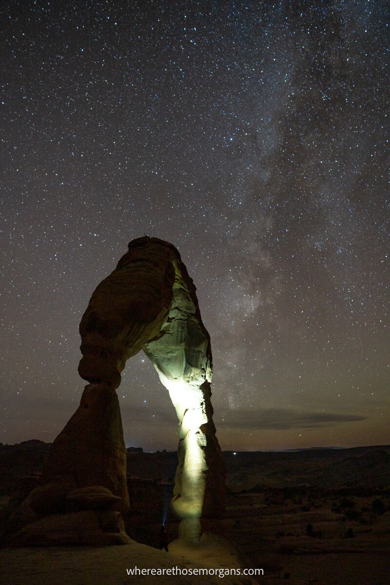 Delicate Arch at night with the milky way and inside arch lit up by flashlight