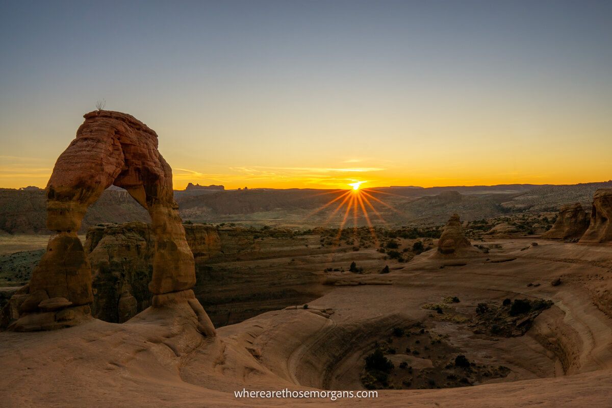 Starburst with the sun as it disappears over the distant horizon at Delicate Arch in Arches Utah