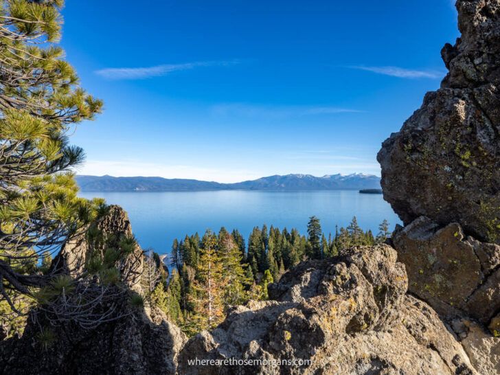 Sharp jagged rocks and trees leading to a deep blue lake and distant mountains view from Eagle Rock trail summit in Lake Tahoe