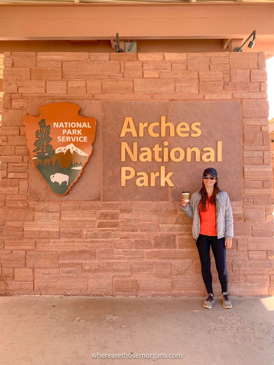 Hiker with coffee at the Arches national park sign