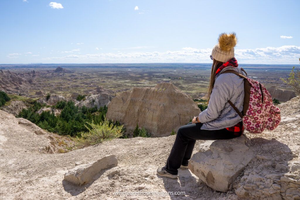 Woman sitting on a rock looking at formations and grass prairies