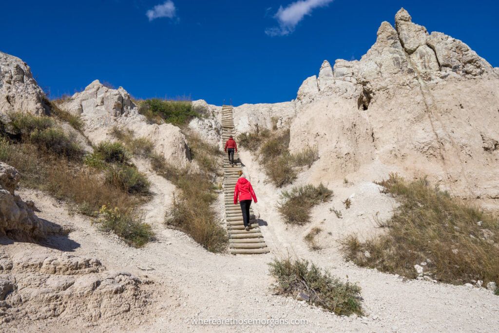 Two hikers climbing a wooden ladder on notch trail in the Badlands