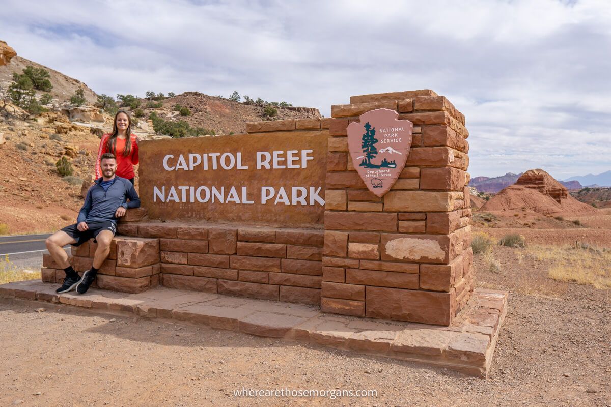 Man and woman sitting on a stone entrance sign to Capitol Reef, a great photo spot