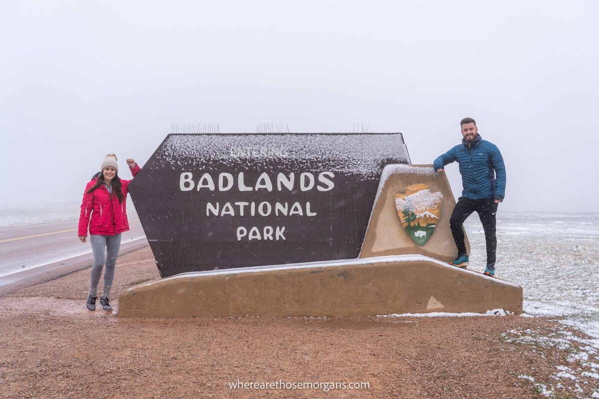 Two people posing with the Badlands National Park sign
