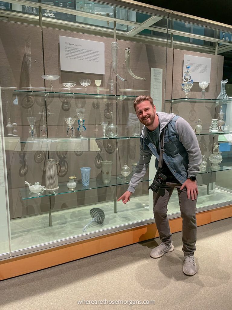 Man smiling and pointing to a glass umbrella, one of the hidden objects at the Corning Museum of Glass