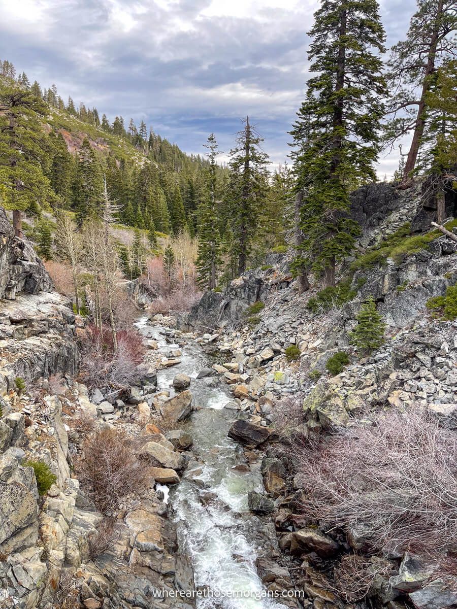 Narrow creek rushing through a rocky landscape with trees and clouds