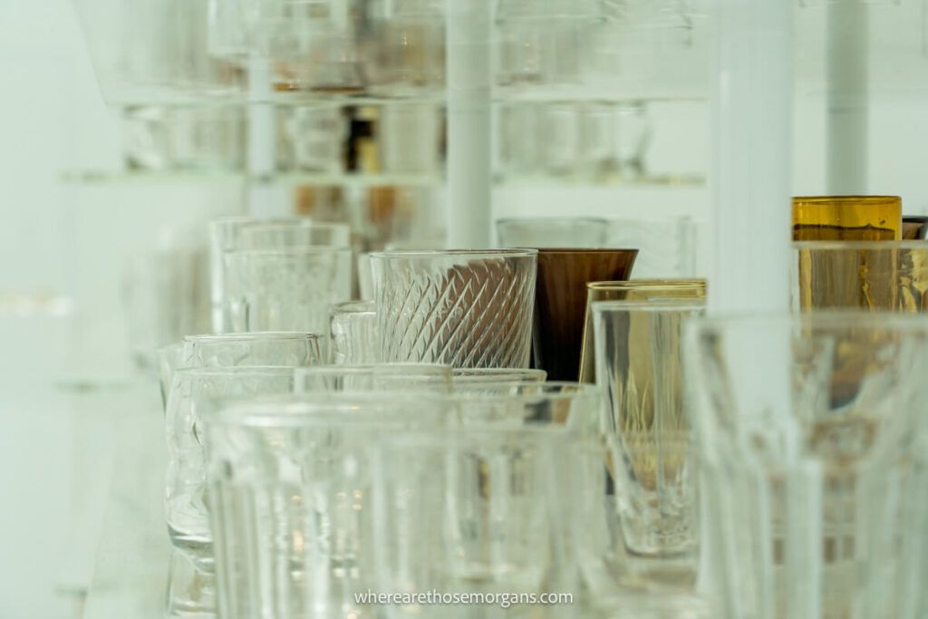 Many glass cups and vases sitting on a shelf