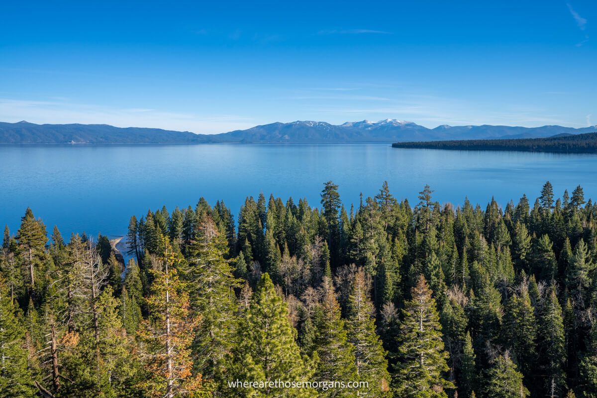 Deep blue lake with green trees and distant mountains