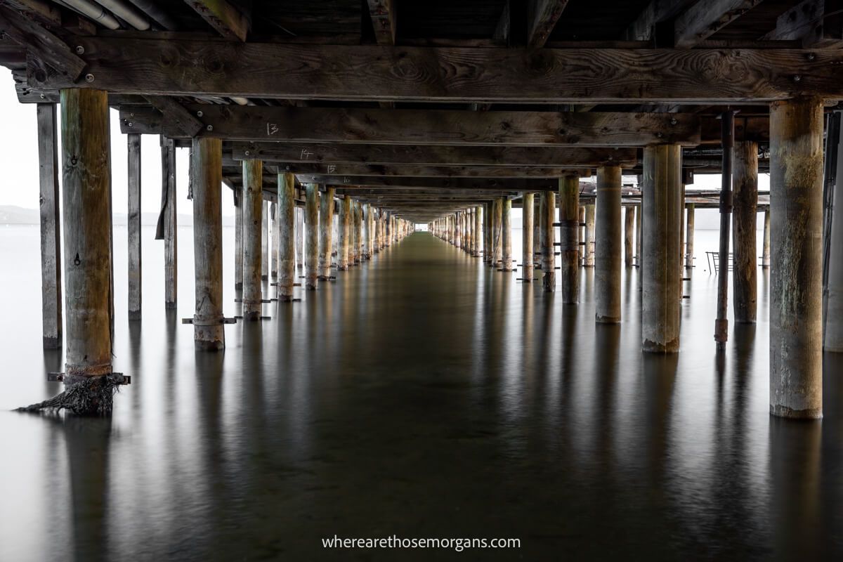 Underneath a long wooden pier at dawn with still water