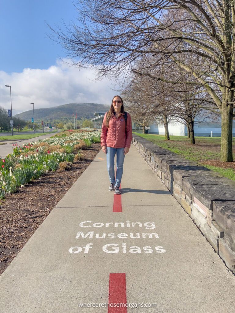 Woman walking on the sidewalk towards the Corning Museum of Glass