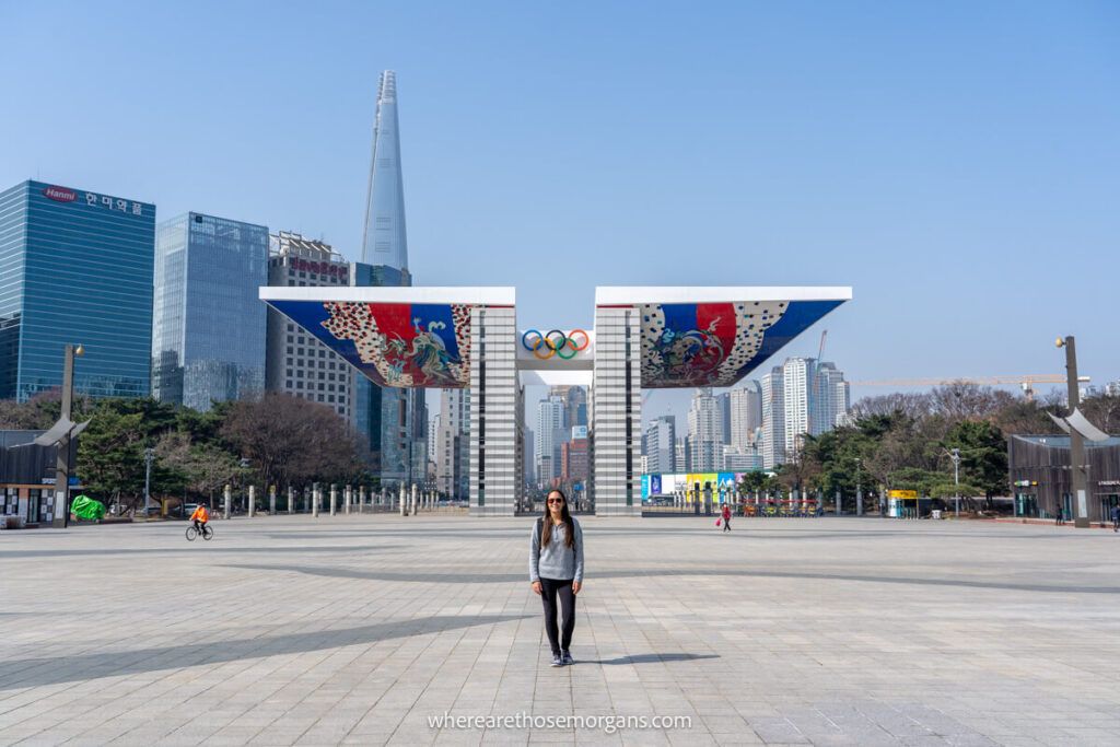 Woman standing in front of the Olympic Gate with Lotte World Tower in the background