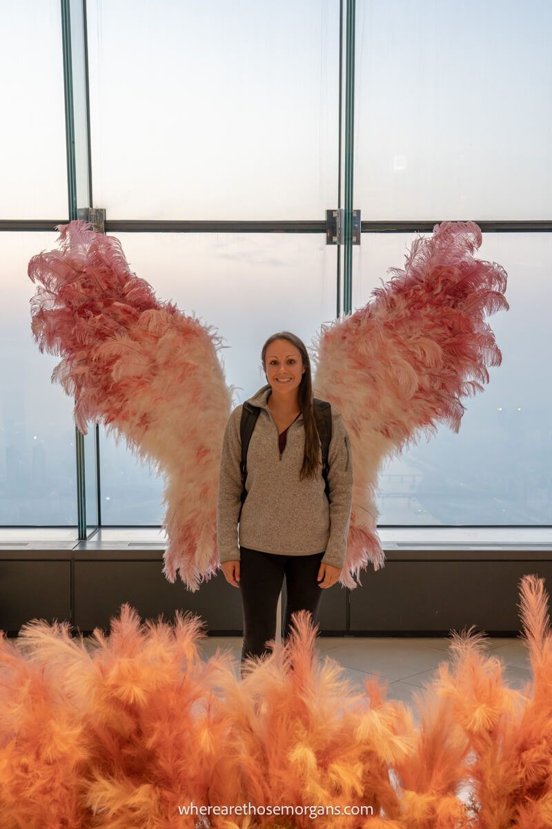 Tourist posing for a photo in pink feathery angel wings