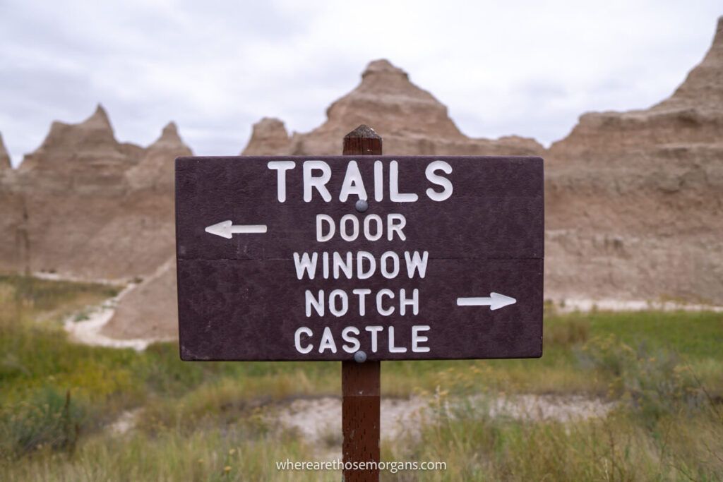 A brown wooden sign for doors, window, notch and castle hiking trails