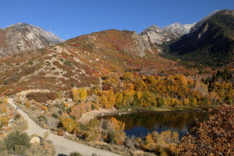 Reservoir and hiking trail surrounded by colorful leaves and mountains