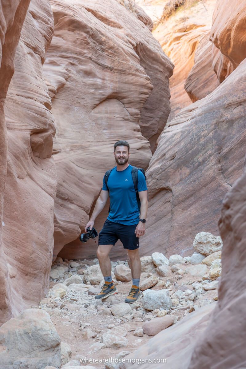 Hiker with camera inside a narrow slot canyon hiking in Utah