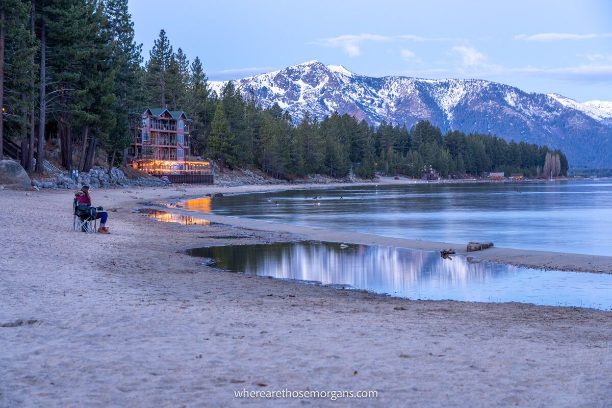Tourist sat on a beach waiting for sunrise with mountains in the background