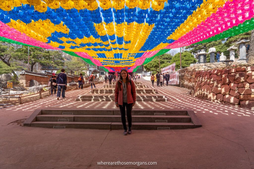 Woman posing for a photo under a colorful exhibit at Bongeunsa Temple