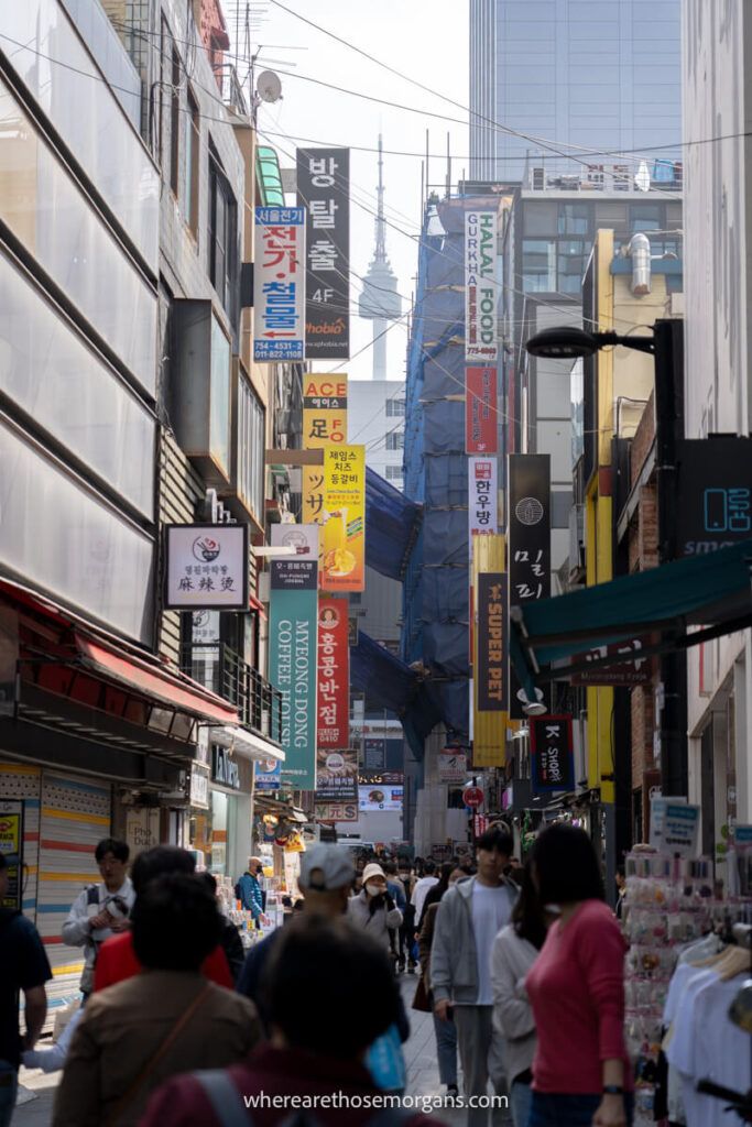 A narrow street in Myeongdong with colorful signs and large crowds