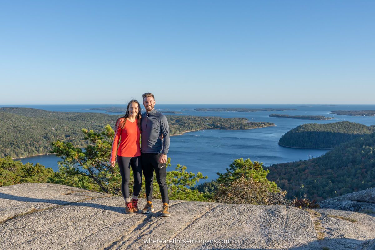 Two hikers taking a photograph at the summit of a mountain in Acadia national park
