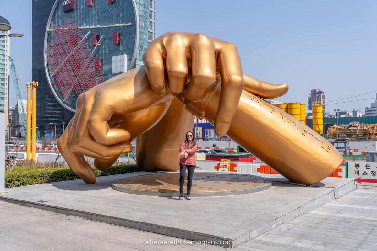 Woman posing for a photo with the famous golden hands of Gangnam