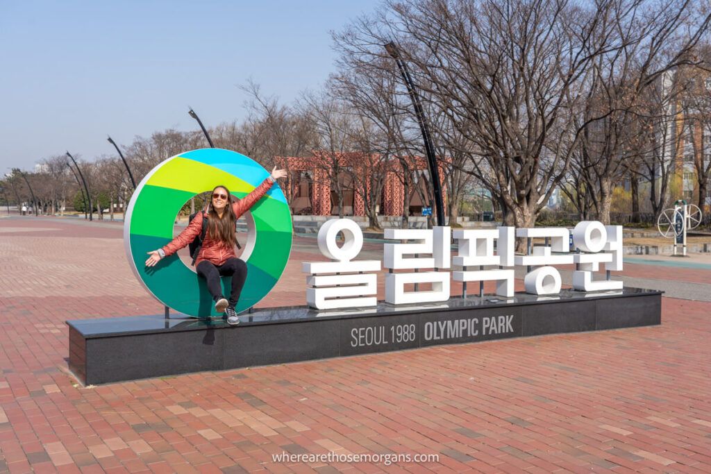 Woman posing for a photo with the 1988 Olympic Park Sign a must do in Seoul