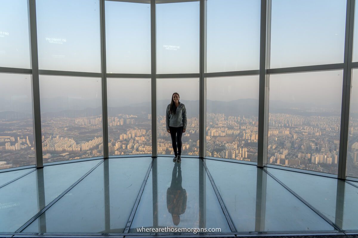 Woman standing on a glass floor at the top of Lotte World Tower