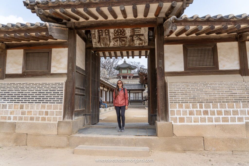 Woman standing inside a wooden door frame inside Changdeokgung Palace