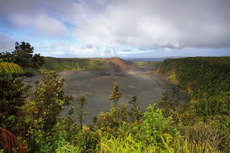 Kilauea Iki crater trail in Hawaii with colorful vegetation surrounding black soil