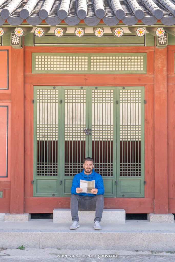 Man sitting on a wooden step inside Deoksugung Palace