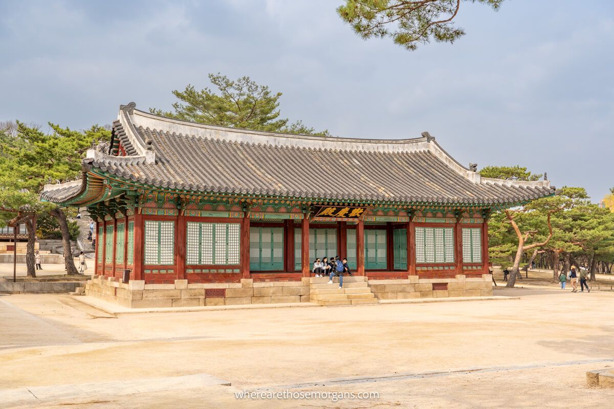 Visitors sitting in front of Tongmyeongjeon Hall on a warm spring day in Seoul