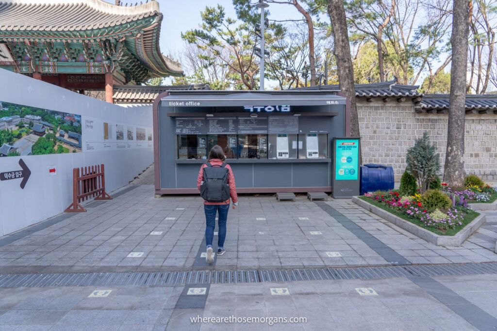 Tourist walking by the ticket booth for Deoksugung Palace