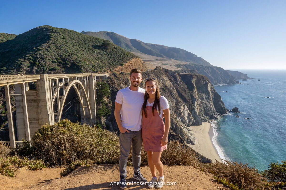Couple standing together in front of Bixby Bridge on the California Pacific Coast Highway on a sunny day