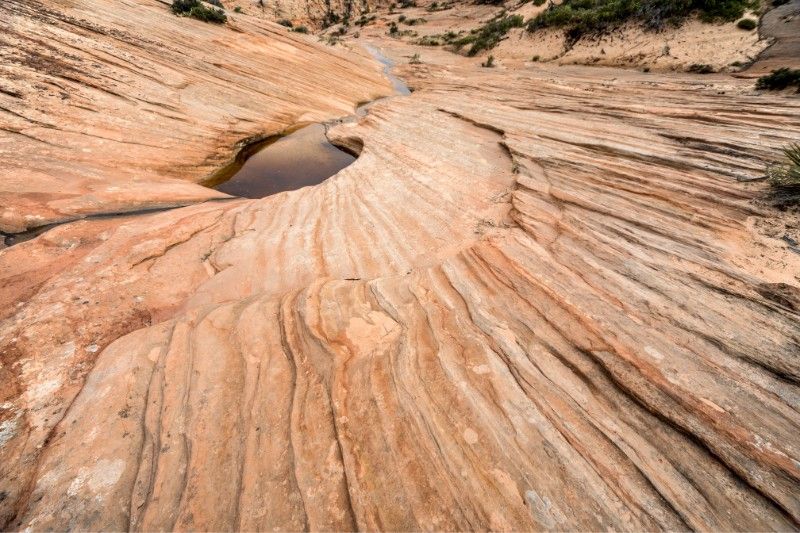 Swirling patterns on rocks leading to smooth circular holes filled with water