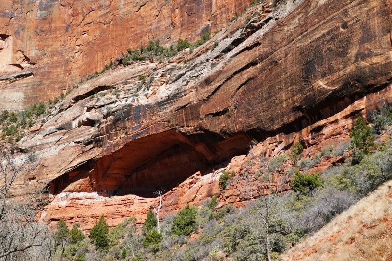 Eroded sandstone shaped like an eye in a tall red rock cliff