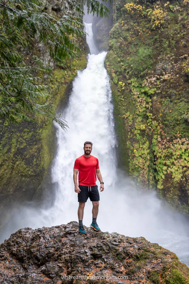 Hiker stood on a rock in the middle of a waterfall in Oregon