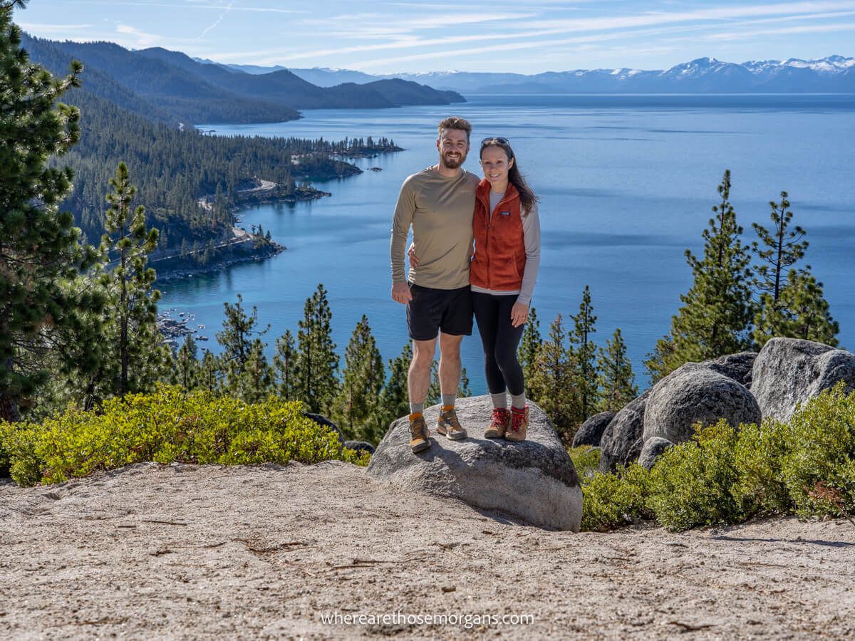 Couple standing together at the summit of a hike in Lake Tahoe on a sunny but cool day
