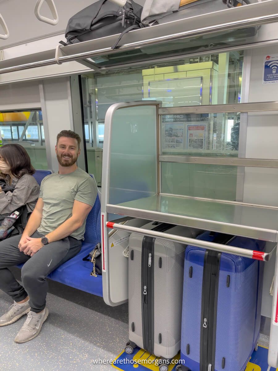 Man sitting on a train in Japan with two backpacks and suitcases fully packed for a trip