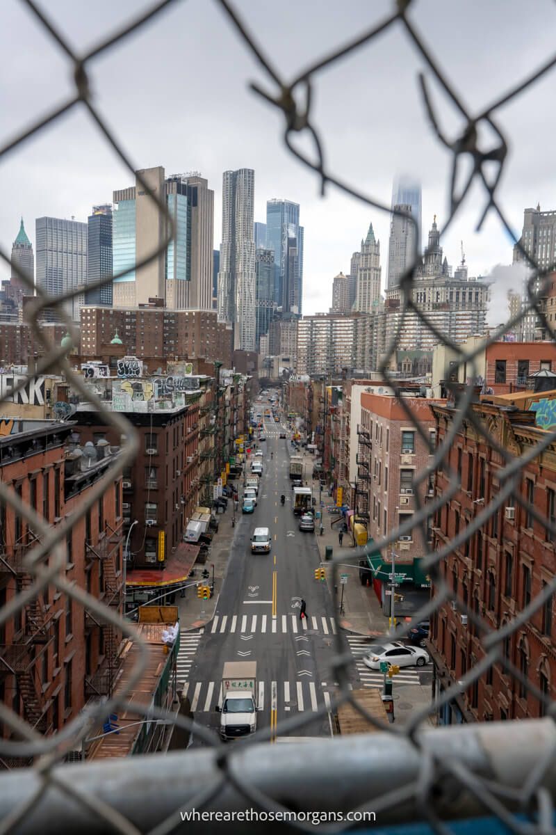 City street from above and through a hole in a mesh fence on a cloudy day